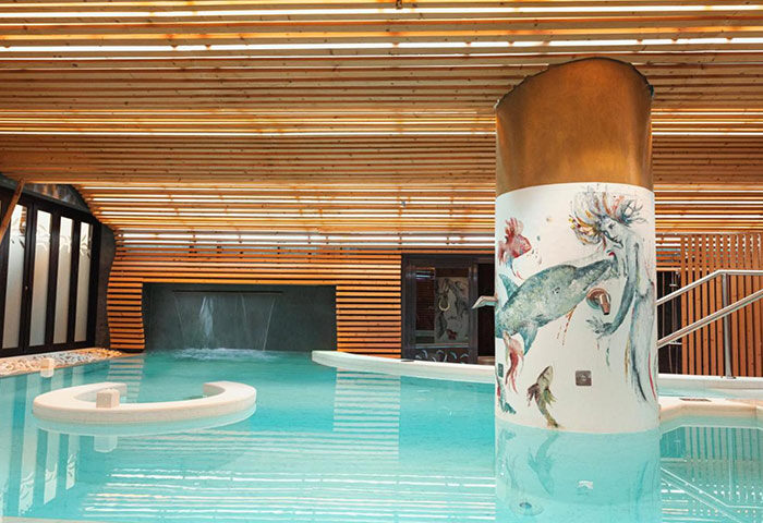 Bohemia Suites & Spa adults-only luxury gay hotel in Gran Canaria. Interior view of the spa pool with artistic pillar and waterfall.