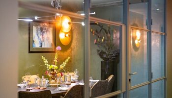 Boutique Hotel Albus Amsterdam Centre dining room. View through glass doors. Best gay hotel Amsterdam, stylish interior, table setting.