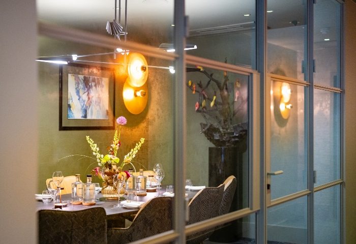 Boutique Hotel Albus Amsterdam Centre dining room. View through glass doors. Best gay hotel Amsterdam, stylish interior, table setting.