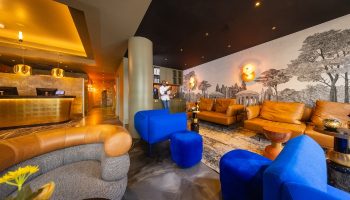 Boutique Hotel Albus Amsterdam Centre lobby. Stylish interior, gay-friendly hotel. Lounge area with blue velvet seating, leather sofas, and reception desk.