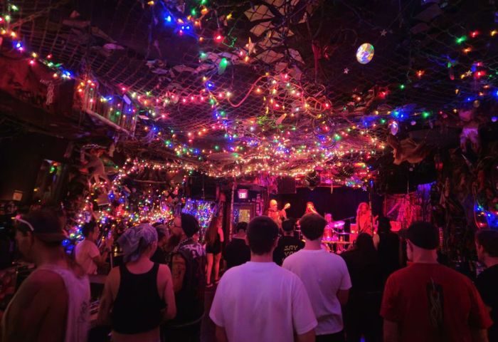 Bovine Sex Club in Toronto: A vibrant, crowded gay club with a live band on stage under a canopy of colorful lights and decorations.