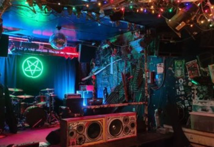 Bovine Sex Club stage in Toronto. Neon pentagram, disco ball, & drum kit. A unique gay men travel destination.