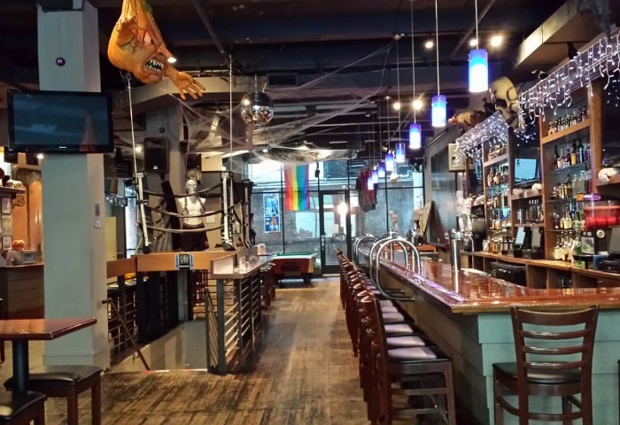 Boxers NYC gay sports bar interior, Halloween decor. Bar, stools, boxing ring, rainbow flag, pool table. Gay travel advice.