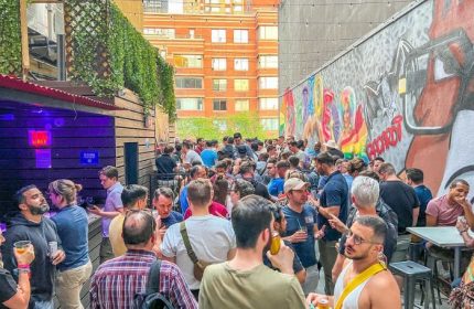 Crowded outdoor patio at Boxers NYC, a popular gay bar. Men gather, drink, and socialize in this vibrant New York City travel destination.