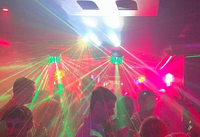 Crowd at a boys' gay bar in Sitges, Spain. Laser lights create a vibrant atmosphere for drinks and socializing. Gay travel destination.