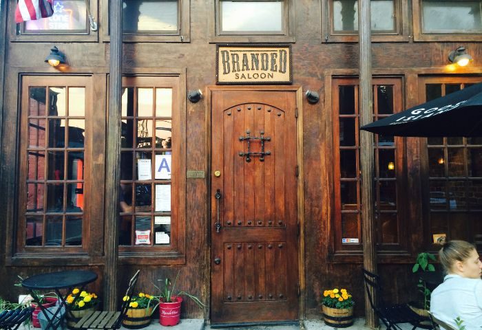 Branded Saloon in New York. Rustic wooden facade, sign above the door. A popular gay bar known for its friendly atmosphere. Gay men travel.