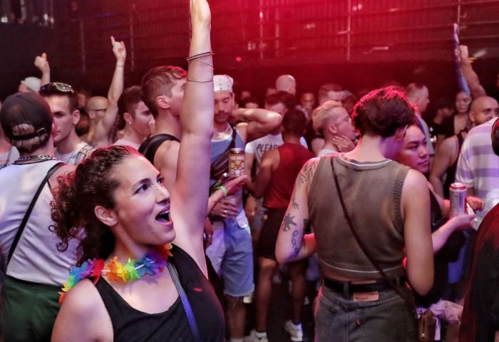 Crowd at Buddies in Bad Times Theatre, Toronto. Gay men and allies dance at a party. Rainbow lei is visible. Gay travel advice.
