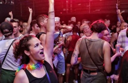 Crowd at Buddies in Bad Times Theatre, Toronto. Gay men and allies dance at a party. Rainbow lei is visible. Gay travel advice.