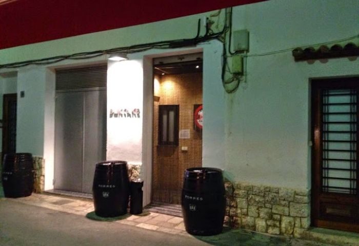 Entrance to Bukkake Cruise Club, a gay cruise club in Sitges. Barrels flank the door of this gay travel destination. Night view.