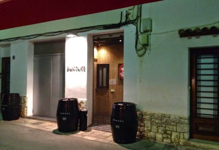 Entrance to Bukkake Cruise Club, a gay cruise club in Sitges. Barrels flank the door of this gay travel destination. Night view.