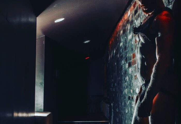 Bunker Bar Sydney: Muscular torso of a man in leather harness. Dark, edgy gay bar atmosphere. Gay travel in Sydney, Australia.
