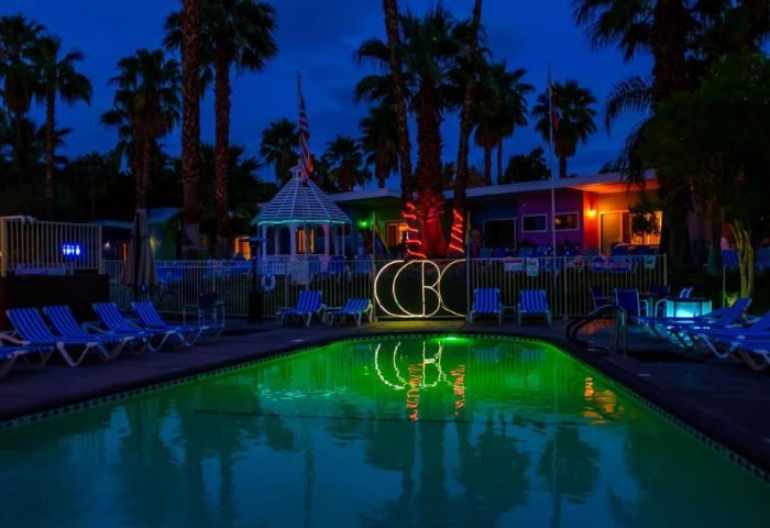 CCBC Resort Hotel pool at night in Palm Springs. Gay cruise travel destination with palm trees and lights.