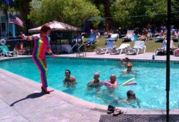 CCBC Resort Hotel's pool scene in Palm Springs. A performer in rainbow attire stands poolside, entertaining guests at this gay cruise destination.