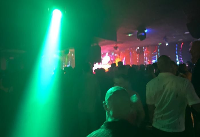 Inside CENTURYON Gay Club in Torremolinos. A crowd of gay men under green lights and disco balls enjoy the nightlife scene.
