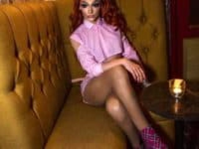 Drag queen at CMYK Bar Wimbledon, a gay bar. Red hair, pink outfit, and plaid heels. A vibrant spot for gay men's travel in Wimbledon.