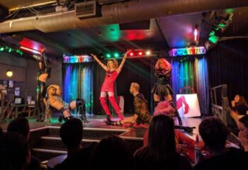 Cabaret Mado gay bar drag show in Montreal. Performers on stage in colorful outfits entertain an audience. Gay travel destination.