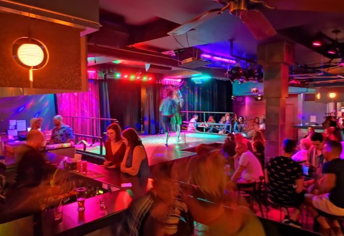 Cabaret Mado gay bar drag show in Montreal. Interior view of the bar with a drag queen performing on stage with colorful lights.