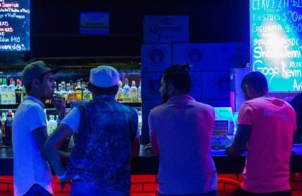 Cabaretito El Taller Gay Bar in Mexico: Men at the bar with drinks. Nightlife scene, gay travel. Neon lights, bar setting, socializing.