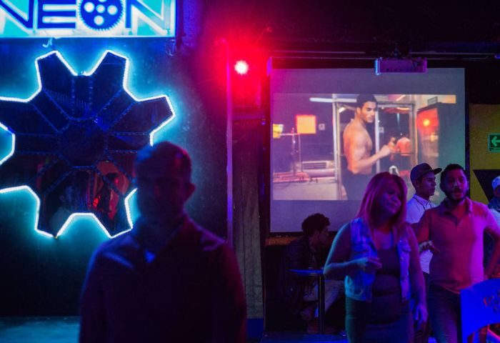 Cabaretito El Taller Gay Bar in Mexico: Gay men at a bar with neon lights and a video playing on a screen. Gay travel advice in Mexico City.