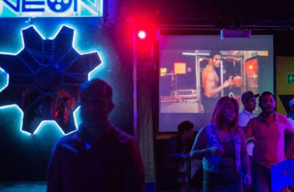 Cabaretito El Taller Gay Bar in Mexico: Gay men at a bar with neon lights and a video playing on a screen. Gay travel advice in Mexico City.