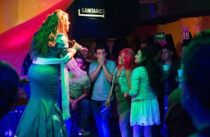 Drag queen performing at Cabaretito El Taller gay bar in Mexico. Crowded venue with excited audience enjoying the show. Gay nightlife.
