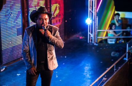 Singer at Cabaretito Fusion Gay Bar in Mexico. Man in cowboy hat performing on stage with colorful lights. Gay travel nightlife.