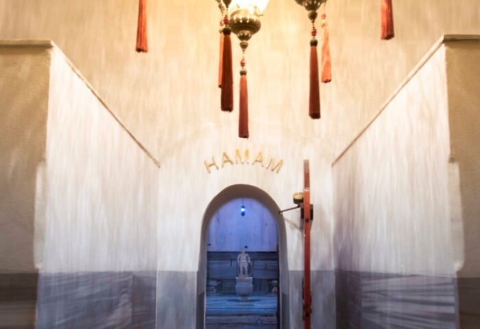 Cagaloglu Hamam entrance in Istanbul. Arched doorway to Turkish bath, with hanging lamps and 'Hamam' sign. Gay travel advice.
