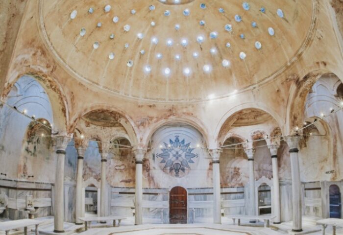 Cagaloglu Hamam interior, Istanbul. Dome with light holes, columns, arches, and marble benches. Gay travel advice, Turkish bath.