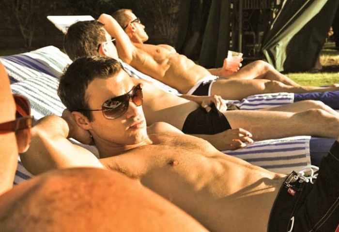 Gay Accommodation: Men relax by the pool at Canyon Club Hotel, a gay resort in Palm Springs. Sunbathing, swimming, and cocktails.