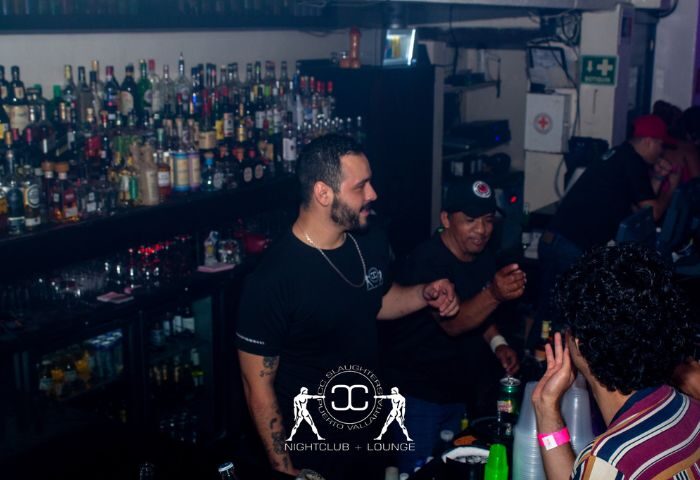 Inside CC Slaughters Nightclub, a popular gay bar in Puerto Vallarta. People are enjoying drinks at the bar. Nightlife scene.