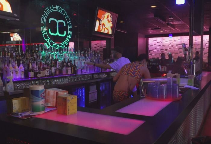 Slaughters Night Club, a gay bar in Puerto Vallarta, features a fully stocked bar, neon lights, and patrons enjoying the nightlife.