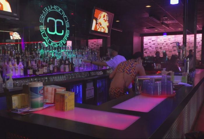 Slaughters Night Club, a gay bar in Puerto Vallarta, features a fully stocked bar, neon lights, and patrons enjoying the nightlife.