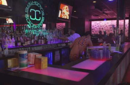 Slaughters Night Club, a gay bar in Puerto Vallarta, features a fully stocked bar, neon lights, and patrons enjoying the nightlife.
