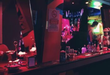 Rome club bar interior with bartender, Vietato Fumare sign, red lighting. Gay travel advice, nightlife scene. Censured Club Rome.