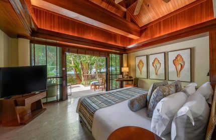 Centara Grand Beach Resort & Villas Krabi room. Gay travel: bedroom with balcony, TV, shell art. Luxury Krabi resort stay.