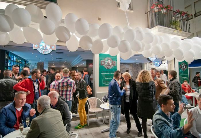 Central Bar Books, a gay bar in Sitges, Spain. Crowd of people, white balloons, and bar interior visible. Gay travel destination.