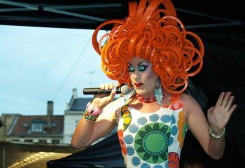 Centralhjornet Copenhagen: Drag queen with orange wig singing. Gay travel advice, LGBTQ+ nightlife in Denmark's capital.