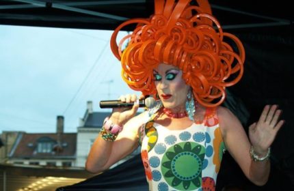 Centralhjornet Copenhagen: Drag queen with orange wig singing. Gay travel advice, LGBTQ+ nightlife in Denmark's capital.
