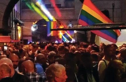 Centralhjornet Copenhagen gay bar crowd with rainbow flags and disco ball. Gay men travel advice in Denmark's capital.