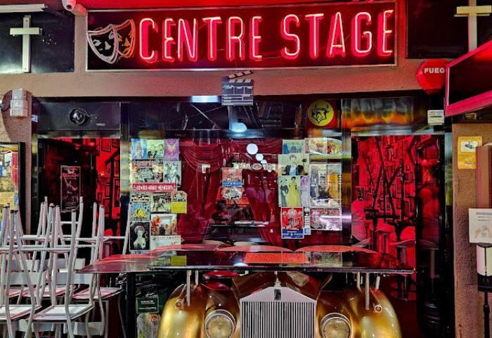 Centre Stage Gay Bar in Gran Canaria. Neon sign, movie posters, and a Rolls Royce create a unique, theatrical ambiance. Gay travel destination.