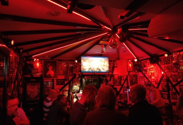 Centre Stage Bar, a gay bar in Gran Canaria, Spain, features red lighting, a disco ball, and patrons enjoying the vibrant atmosphere.