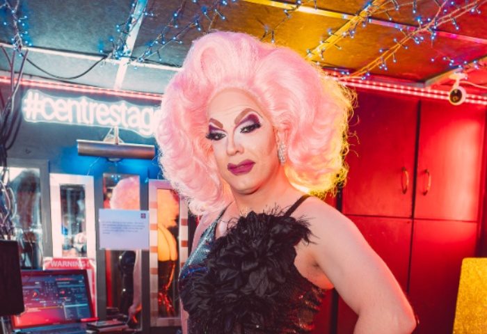 Drag queen at Centre Stage, Manchester. Pink wig, sequin dress, and feather boa. Gay travel advice, LGBTQ+ nightlife.
