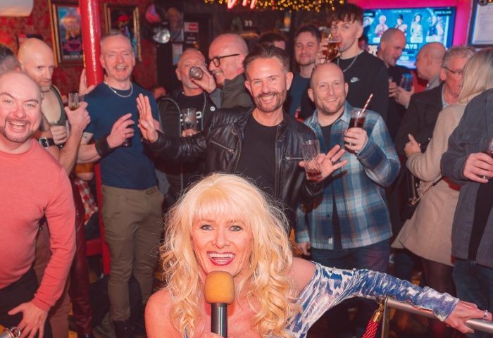 Centre Stage Manchester: Drag queen performance in a gay bar. Crowd of gay men enjoying the show, drinks in hand, lively atmosphere.