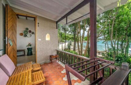 Samed Villa Resort beachfront view. Gay hotel near gay beach bars, Thailand. Balcony with chairs overlooking the ocean and tropical trees.