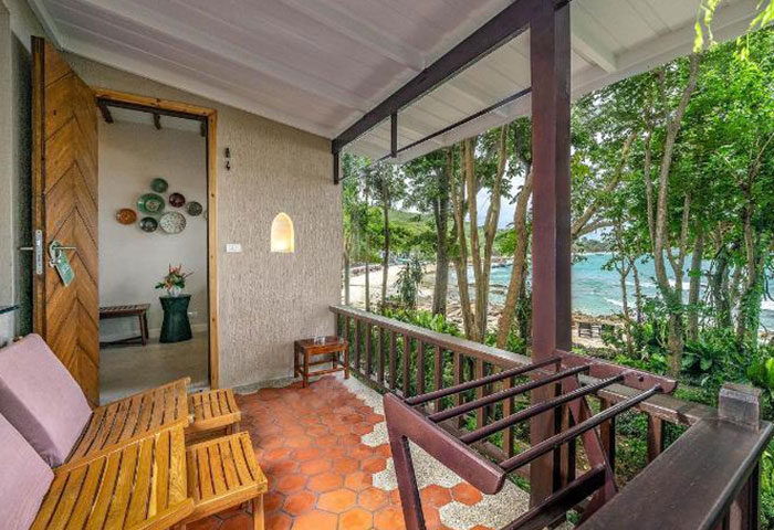 Samed Villa Resort beachfront view. Gay hotel near gay beach bars, Thailand. Balcony with chairs overlooking the ocean and tropical trees.