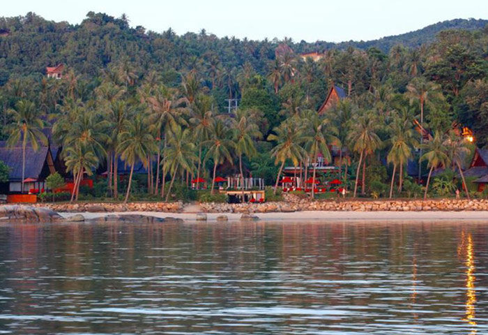 Kupu Kupu Phangan Beach Villas, a gay-friendly luxury hotel. Beachfront view with palm trees and villas. Tropical Koh Phangan paradise.
