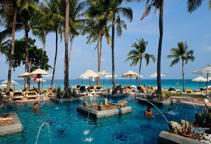 Centara Grand Beach Resort Samui beachfront pool view. Gay hotel with palm trees, sun loungers, and turquoise water. Tropical paradise.