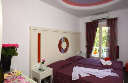 Matogianni Hotel, Mykonos. Budget gay hotel room in city center. Twin beds, flowers, balcony view. Perfect for gay travel in Mykonos.