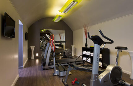 Duo Hotel Paris gym. Cheap city center gay hotel with fitness equipment, including treadmill, exercise bike, and weights for a workout.