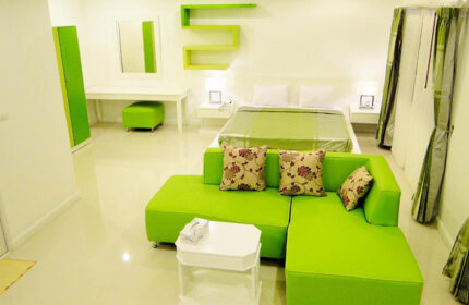 Sansuk Sauna Guesthouse room. Adults-only hotel with pool and sauna. Green couch, bed, and decor in this cheap gay hotel.